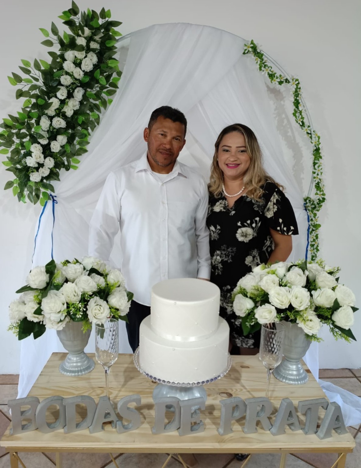Casal celebrando suas bodas junto ao bolo e aos arranjos de flores