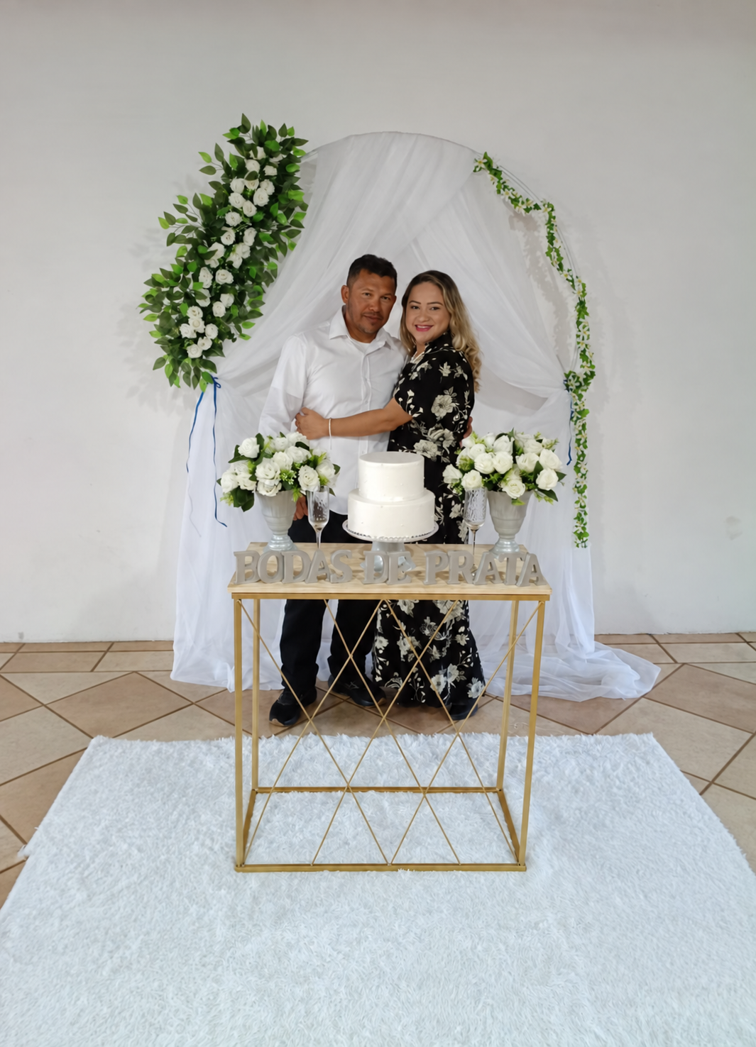 Casal celebrando suas bodas diante do bolo e da decoração floral