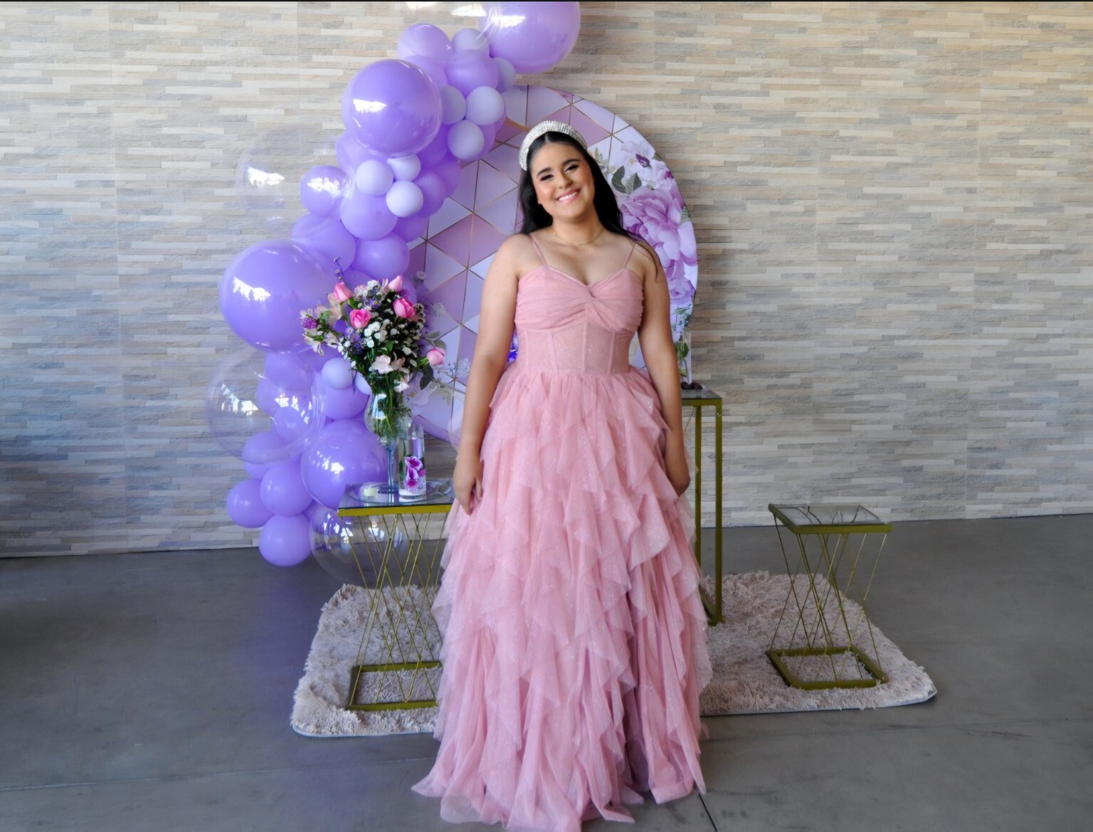 Debutante em vestido rosa diante de uma decoração com balões lilás